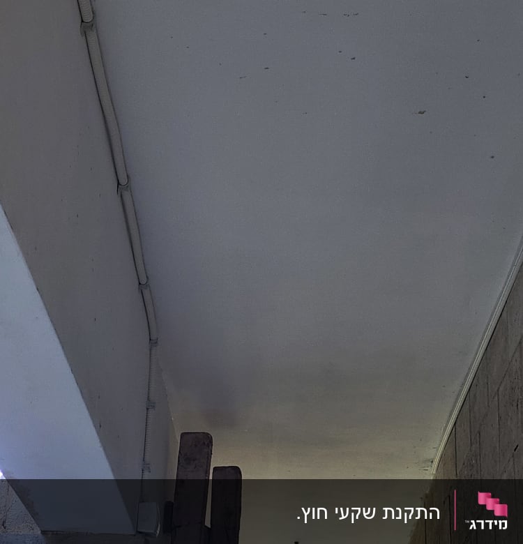 צינור חשמל לבן מותקן על תקרה לבנה